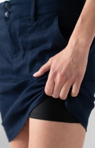 Person wearing a navy blue skort with a plain background