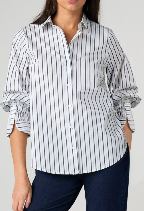 Person wearing a white and Navy striped shirt with rolled-up sleeves on a plain background