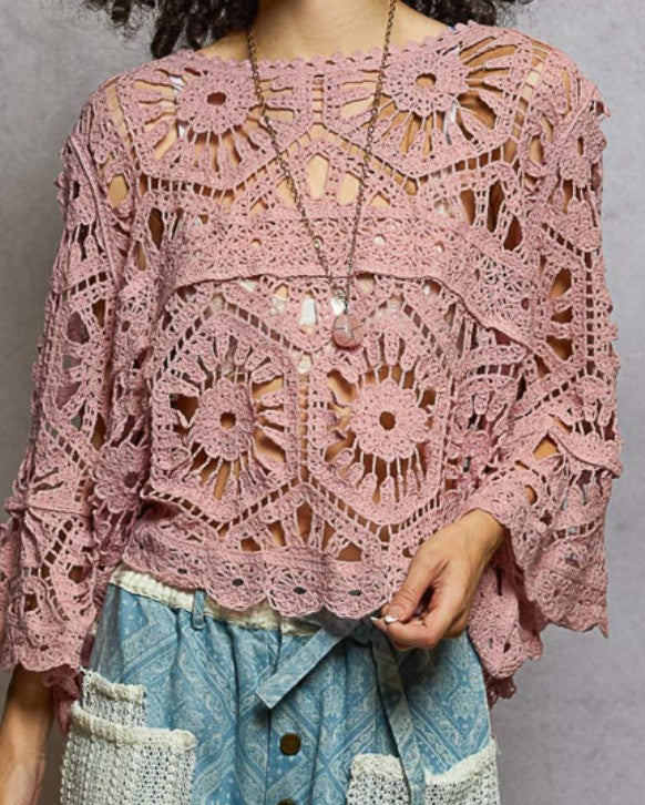 Pink crochet top worn by a person against a gray background