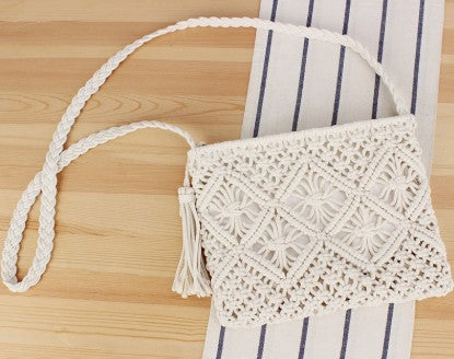 White crochet handbag with tassel on a wooden surface