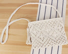 White crochet handbag with tassel on a wooden surface