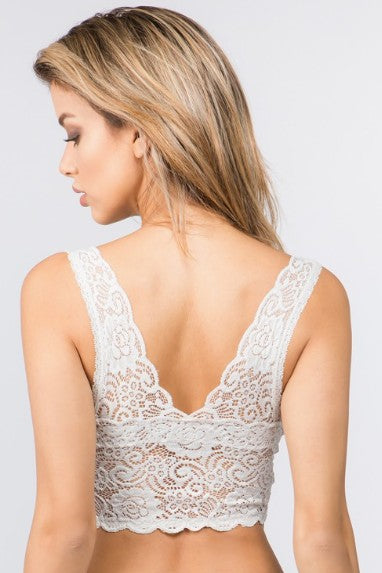 Woman wearing a white lace bralette on a light gray background
