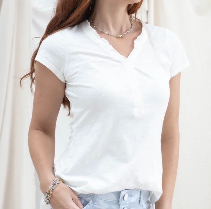 Lady wearing a white tee with detail around the neck in front of a white background.