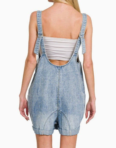 Denim overalls worn by a person on a white background