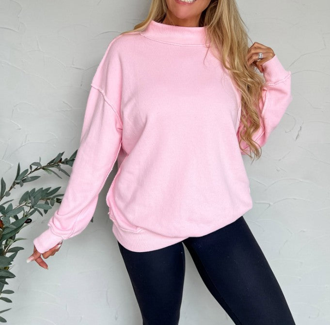 Person wearing a pink sweatshirt and black leggings against a white background