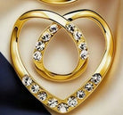 Gold heart-shaped ring with clear rhinestones, shown in a close-up product shot on a beige and dark navy background.
