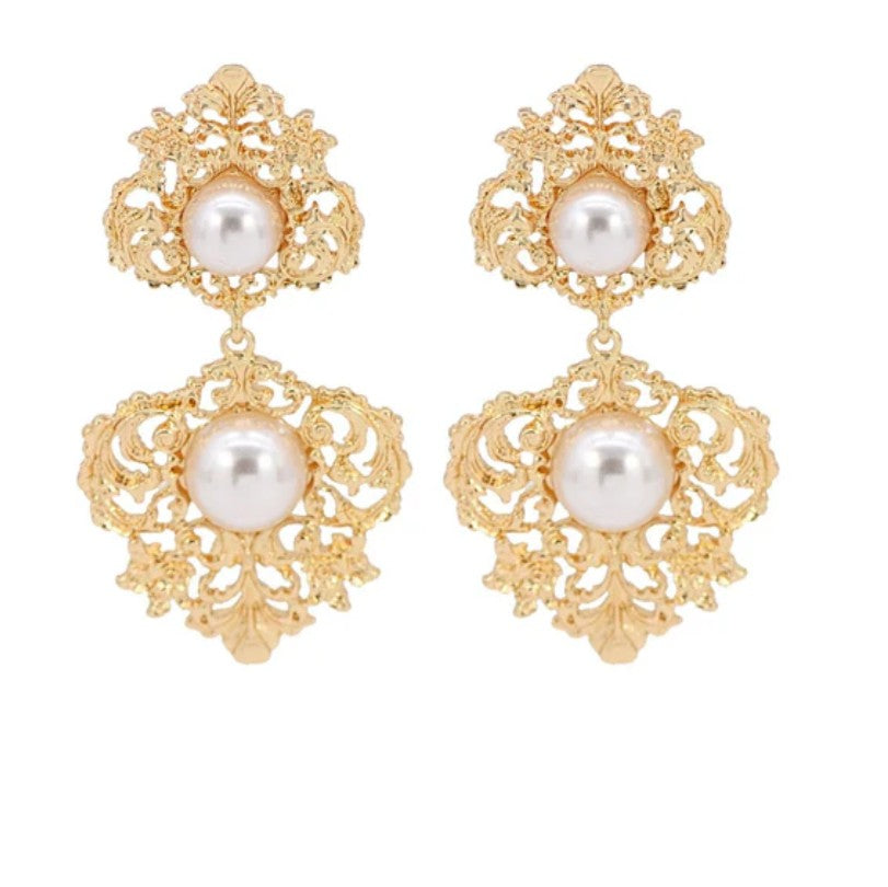 Gold earrings with pearl drops on a white background