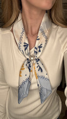 Silky blue and gold botanical pearl magnetic scarf with soft satin fabric and pearl clasp accent.